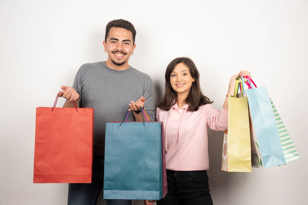 Coppia felice con shopping bag in piedi su sfondo bianco. Foto di alta qualità - Foto, immagini