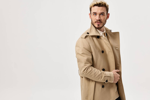 muž v béžovém kabátu podzimní styl módní účes studio - Fotografie, Obrázek