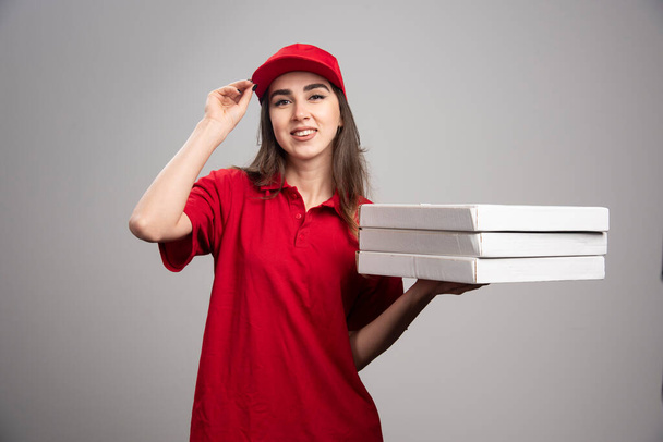 Mujer partera sosteniendo pizzas sobre fondo gris. Foto de alta calidad - Foto, Imagen