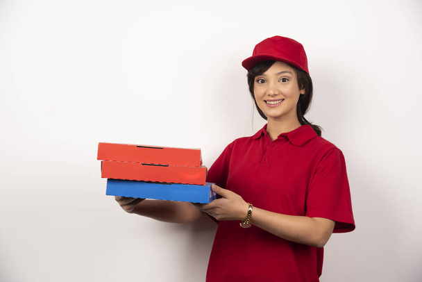 Ευτυχισμένη ντελιβεράς που κρατάει τρεις κάρτες πίτσα. Υψηλής ποιότητας φωτογραφία - Φωτογραφία, εικόνα