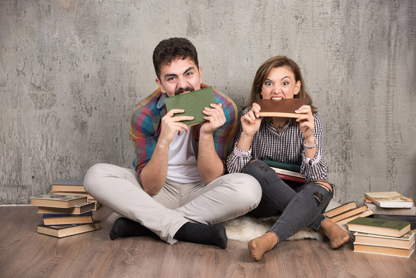Photo of angry couple biting books. High quality photo - Foto, afbeelding