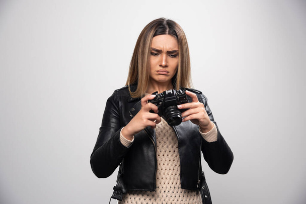 黒の革のジャケットの若い女性は、カメラと真剣に、専門的な方法で写真を撮る。高品質の写真 - 写真・画像