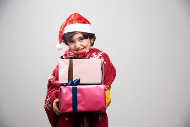 Весела дитина у формі Санти дарує різдвяні подарунки. Фотографія високої якості - Фото, зображення
