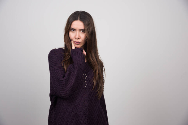 Young woman in purple sweater standing on gray background. High quality photo - Photo, image