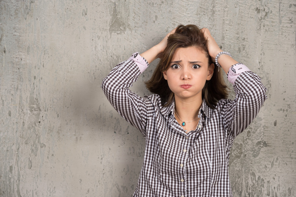 Photo of worried woman in plaid shirt holding her head . High quality photo - Foto, Bild