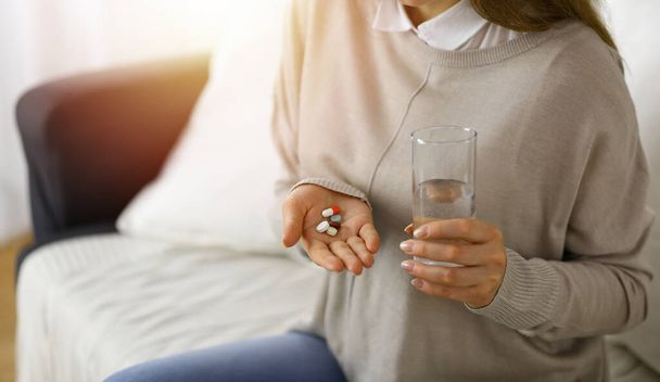 Close-up woman holding pills time to take medications, cure for headache. Medicine concept during self isolation and Coronavirus pandemic - 写真・画像