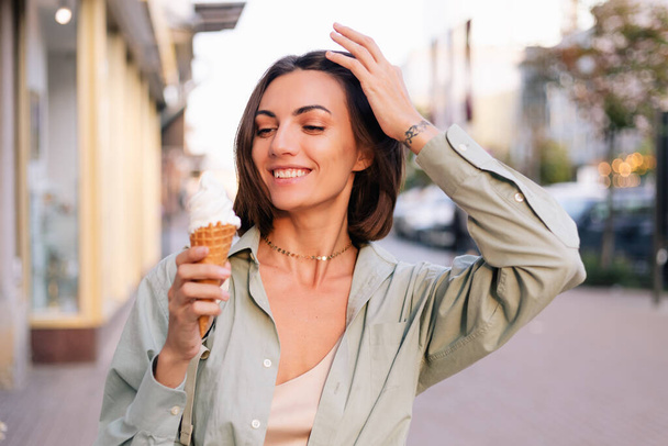 Mujer al aire libre en verano al atardecer teniendo helado cono positivo feliz juguetón en la calle de la ciudad - Foto, Imagen
