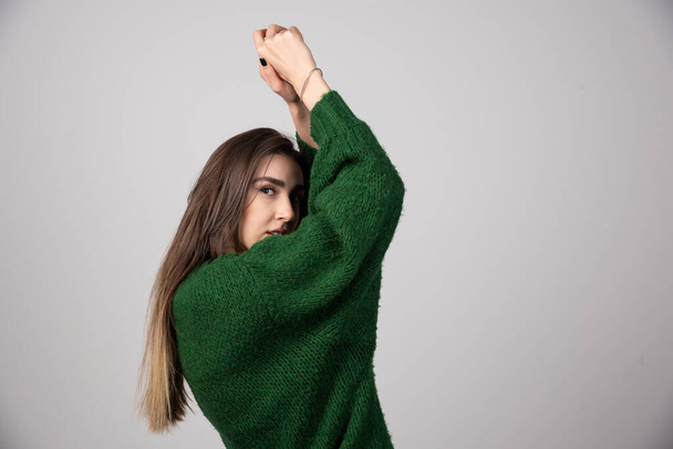 Fiatal nő zöld pulóverben, szürke háttérrel. Kiváló minőségű fénykép - Fotó, kép