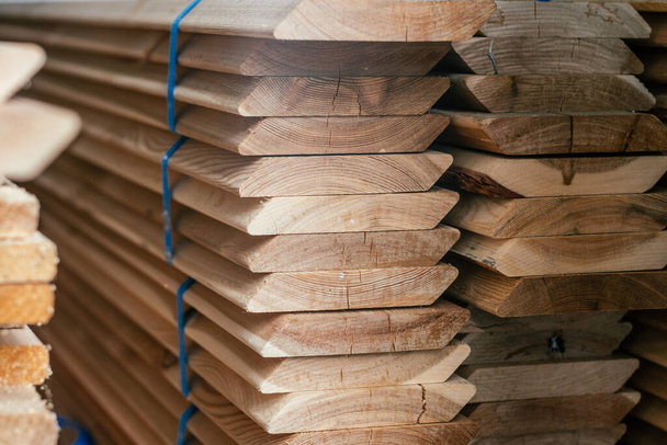 View of ends of stacked edged larch boards with beveled edge, planken for construction of fence or cladding house, timber prepaired for building - Photo, Image