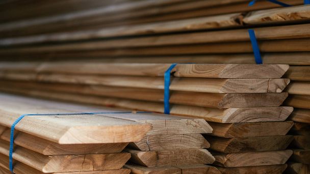 Ansicht der Enden gestapelter, kantiger Lärchenholzplatten mit abgeschrägter Kante, Planken für den Bau von Zäunen oder Verkleidungen, für den Bau vorbereitetes Holz - Foto, Bild