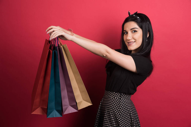 Woman holding her bags on red background - Fotoğraf, Görsel