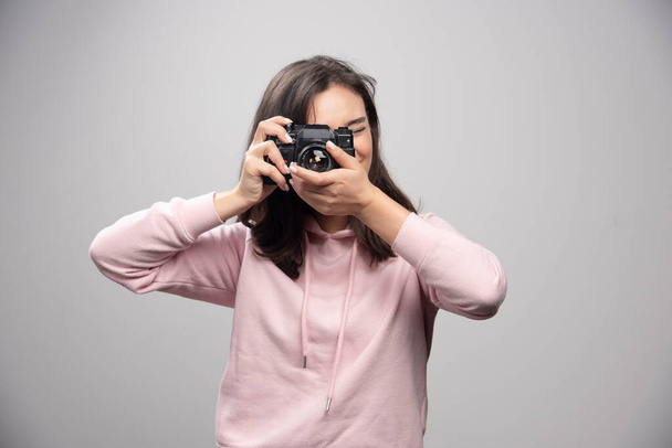 Fiatal nő pulóverben fotózik. Kiváló minőségű fénykép - Fotó, kép