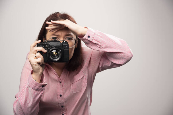 白い背景のカメラで写真を撮る女性。高品質の写真 - 写真・画像