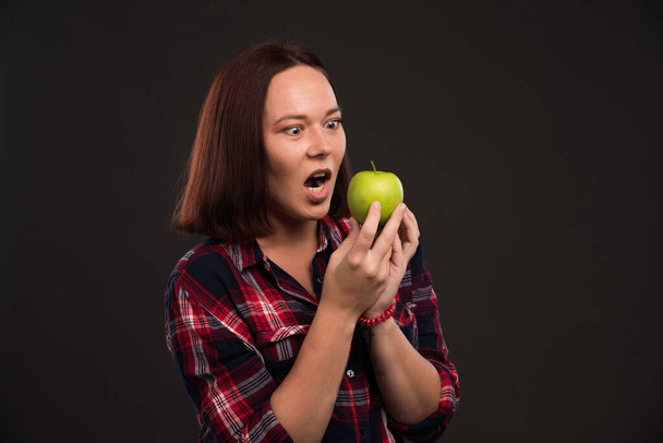 Female model in fall winter collection outfits holding a green apple and looking with appetite. High quality photo - Photo, Image