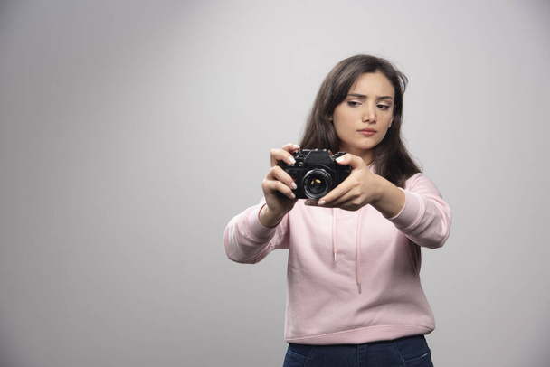 Hezká mladá žena fotí s kamerou přes šedou zeď. Kvalitní fotografie - Fotografie, Obrázek
