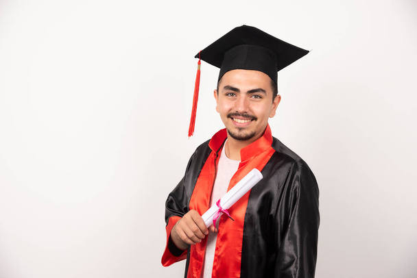 Happy male student with diploma standing on white background. High quality photo - Photo, Image