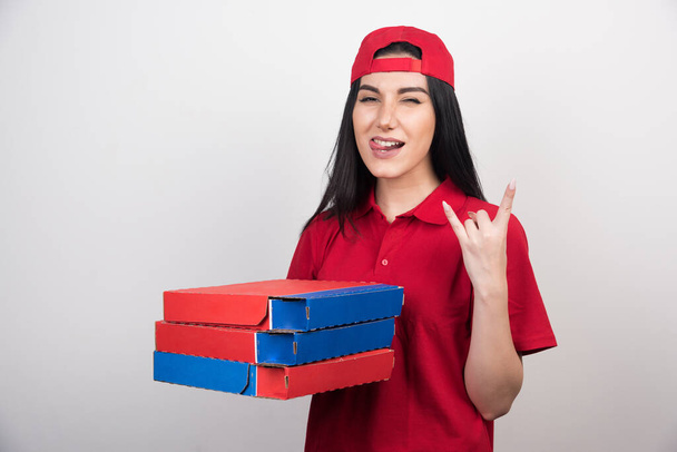 Joven partera con gorra sosteniendo tres cajas de pizza sobre fondo blanco  - Foto, Imagen