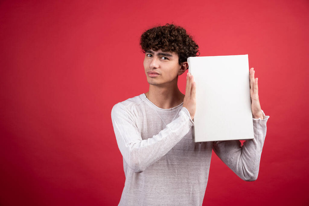 Young boy holding empty canvas on red background. High quality photo - Fotografie, Obrázek