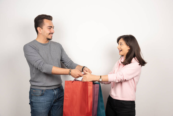 Sweet couple carrying shopping bags on white background. High quality photo - Photo, image