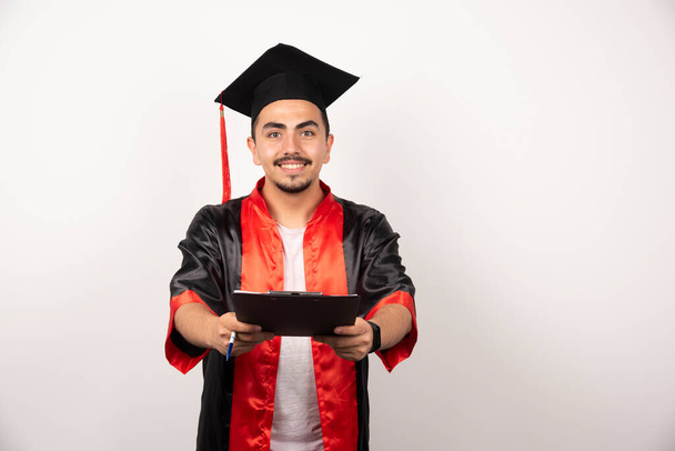 Estudiante graduado positivo mostrando diploma en fondo blanco. Foto de alta calidad - Foto, Imagen