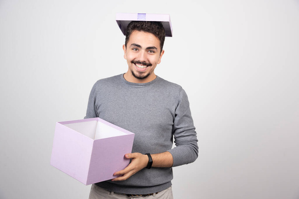 Een glimlachende man die een paarse doos vasthoudt. Hoge kwaliteit foto - Foto, afbeelding