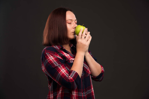 Female model in fall winter collection outfits holding a green apple and smelling it. High quality photo - Photo, Image
