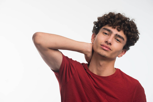 Young model with curly hairs touching his neck. High quality photo - 写真・画像