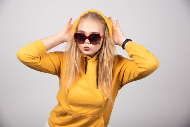 Portrait of pretty girl in yellow hoodie wearing stylish glasses..High quality photo - Fotografie, Obrázek