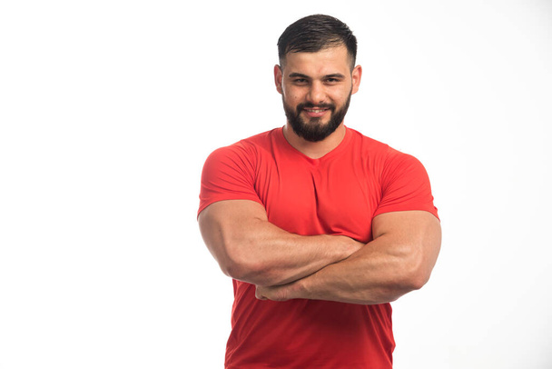 Спортивный человек в красном показывает свои мускулы. Высокое качество фото - Фото, изображение