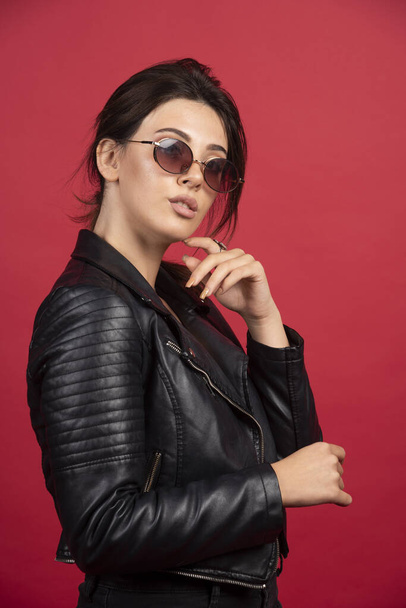 Cool girl in black leather jacket posing in black sunglasses. High quality photo - Fotó, kép