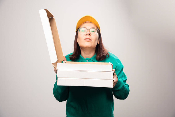 Deliverywoman holding cardboards of pizza on a white background. High quality photo - Photo, Image