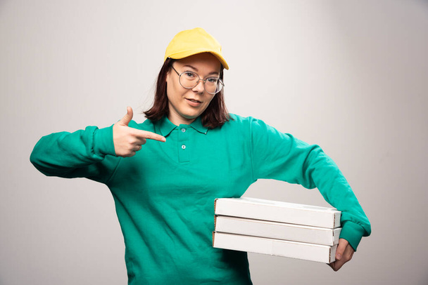 Deliverywoman showing cardboards of pizza on a white background. High quality photo - Photo, Image