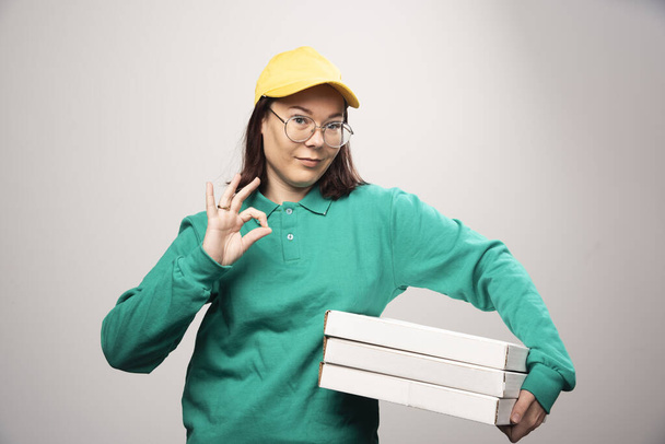 Deliverywoman carrying cardboards of pizza on a white background. High quality photo - Zdjęcie, obraz
