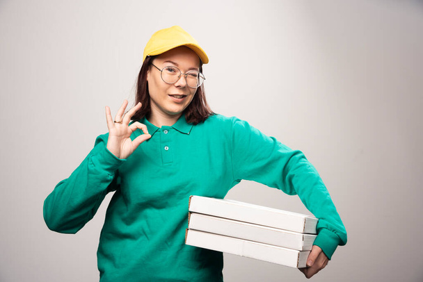 Deliverywoman carrying cardboards of pizza on a white background. High quality photo - Photo, Image