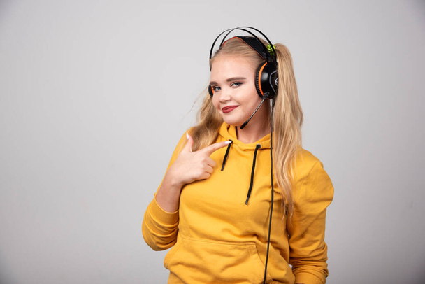 Blonde woman in headphones pointing at herself. High quality photo - Photo, Image