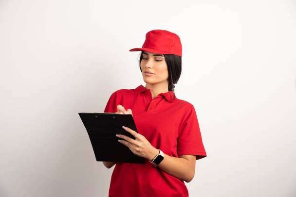 Female courier writing orders on clipboard. High quality photo - Foto, imagen