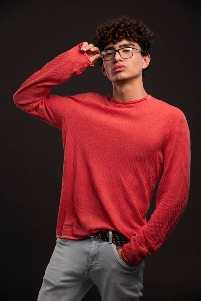 Nuori malli punaisessa paidassa pitelee silmälaseja. Laadukas kuva - Valokuva, kuva
