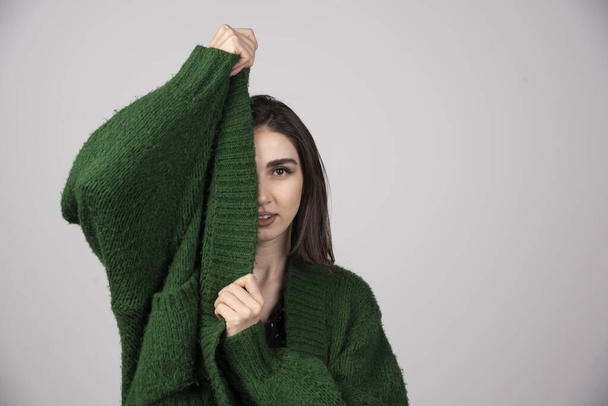 Młoda kobieta ściągająca sweter na szarym tle. Wysokiej jakości zdjęcie - Zdjęcie, obraz