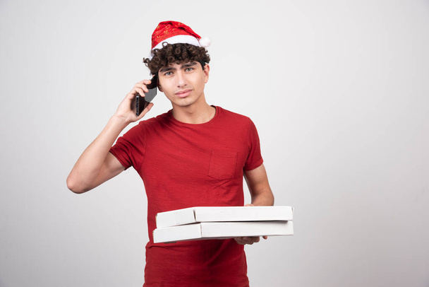Young deliveryman holding cardboards and speaking on phone . High quality photo - Photo, Image