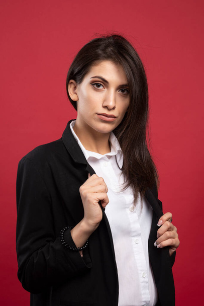 Brunette businesswoman standing on red background. High quality photo - 写真・画像