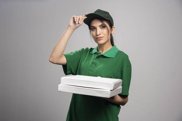Delivery woman holding pizza on gray background. High quality photo - Fotoğraf, Görsel