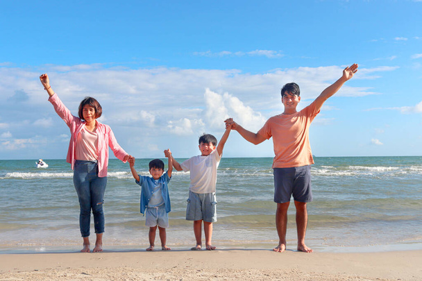 Familia feliz cuatro pasar tiempo y divertirse juntos en las vacaciones de verano, padres alegres niños sostienen y levantan las manos en la playa de arena tropical, descanso y relajante fin de semana. - Foto, Imagen