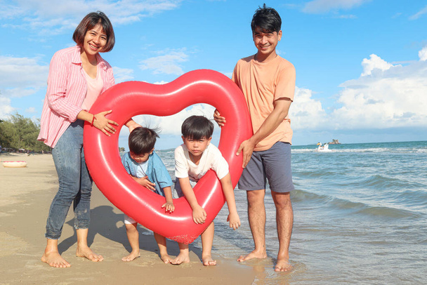 Bonne famille passer du temps ensemble en vacances d'été, parents et enfants avec anneau de natation gonflable rouge courir sur la plage de la mer tropicale, père mère et enfants se reposer et se détendre le week-end  - Photo, image