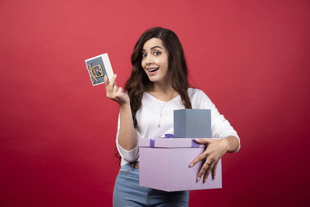 Young woman posing with present on red background. High quality photo - Φωτογραφία, εικόνα