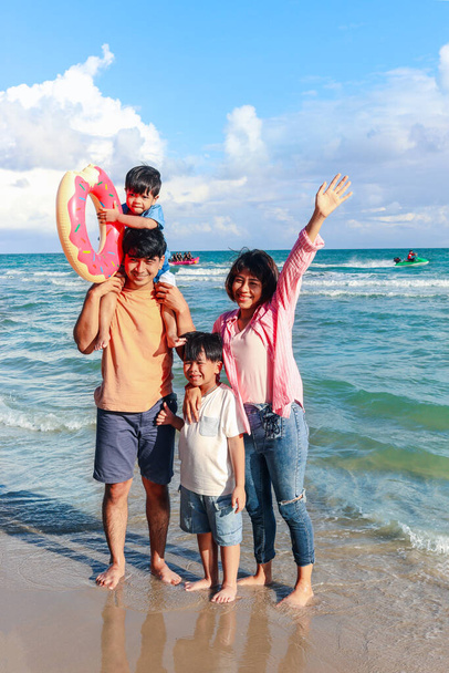 Happy family of four spend time together on tropical sand beach, father and mother playing with kid, daddy carrying cute little son, joyful parents and children on summer holiday vacation. - Photo, Image