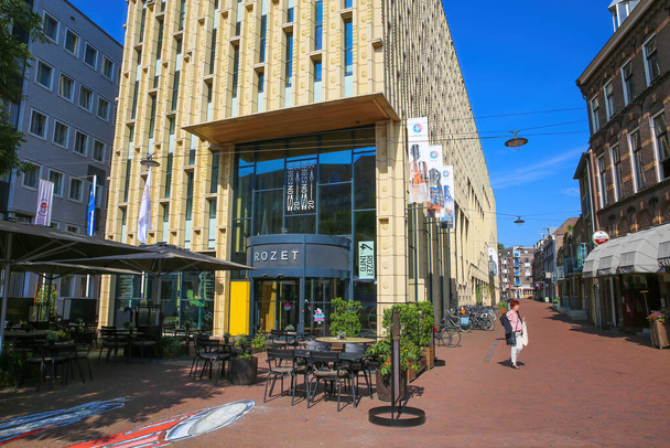 Arnhem (Rozet Centrum), Netherlands - July 9. 2021: View on entrance of modern architecture building in city center with outdoor restaurant cafe against blue summer sky - Foto, afbeelding
