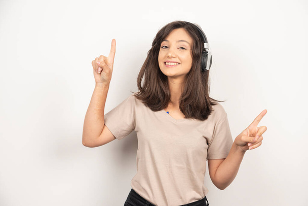 Young woman standing and listening to music in headphones. High quality photo - Foto, afbeelding