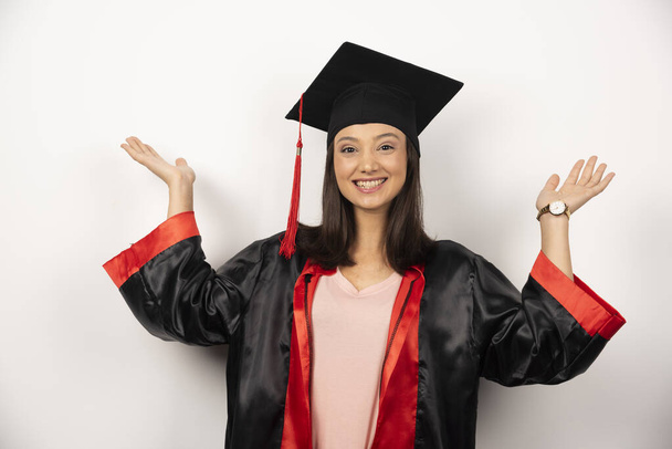 Φρέσκος απόφοιτος με φόρεμα που δείχνει τα χέρια της σε λευκό φόντο. Υψηλής ποιότητας φωτογραφία - Φωτογραφία, εικόνα