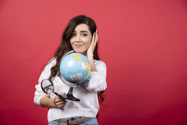 Gelukkige vrouw poseren met globe en vergrootglas. Hoge kwaliteit foto - Foto, afbeelding