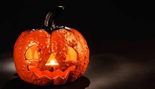 Keramická dýně s strašidelný obličej se svíčkou zářící uvnitř jako lucerna pro halloween noc na černém pozadí s kopírovacím prostorem - Fotografie, Obrázek